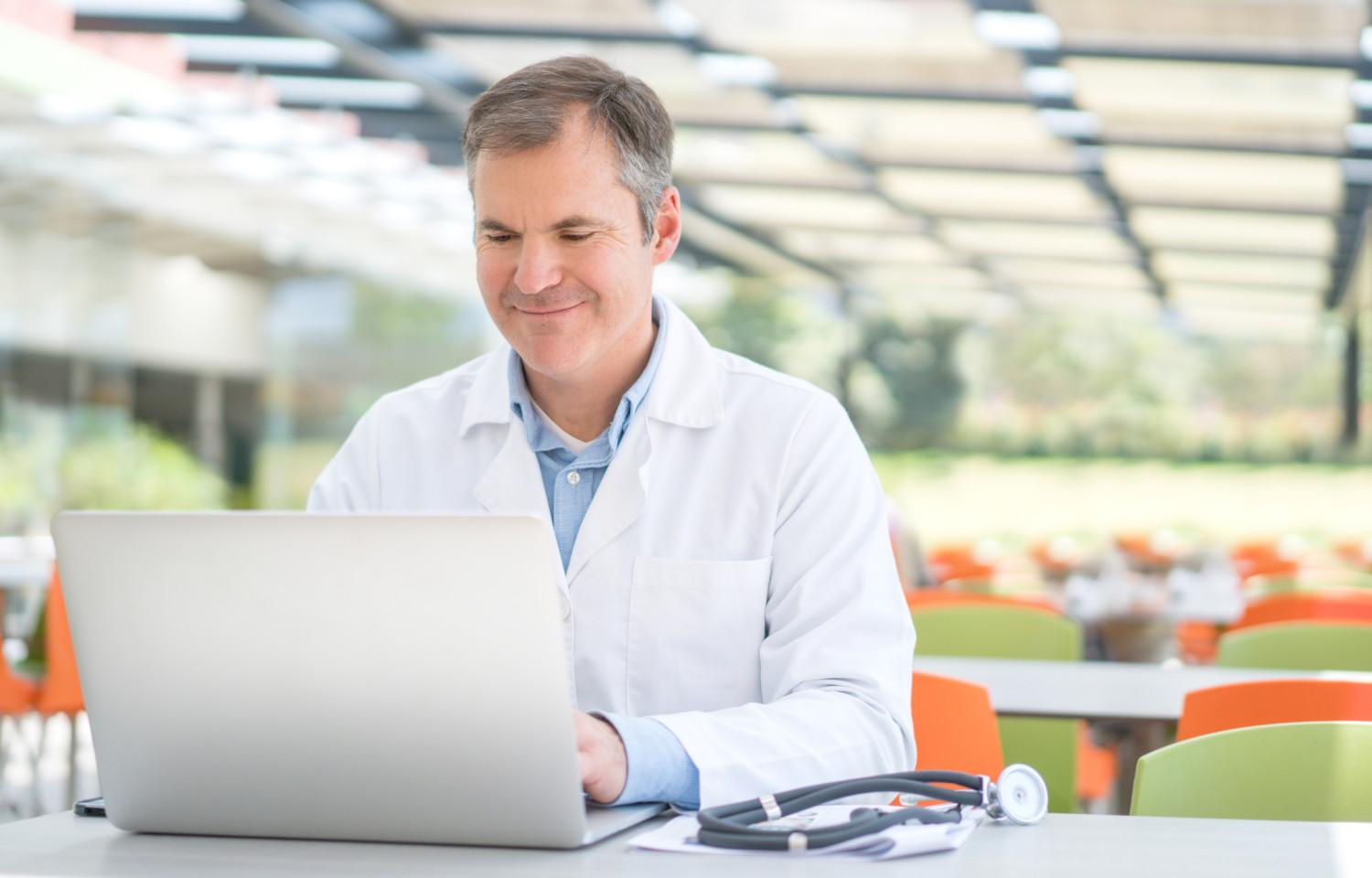stock photo focused serious middle aged old male physician working with medical prescriptions and laptop busy
